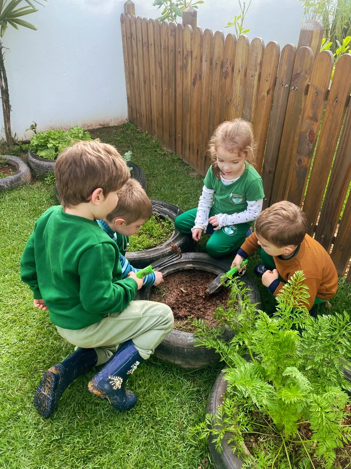 Crianças cuidando juntas das plantas na horta da escola