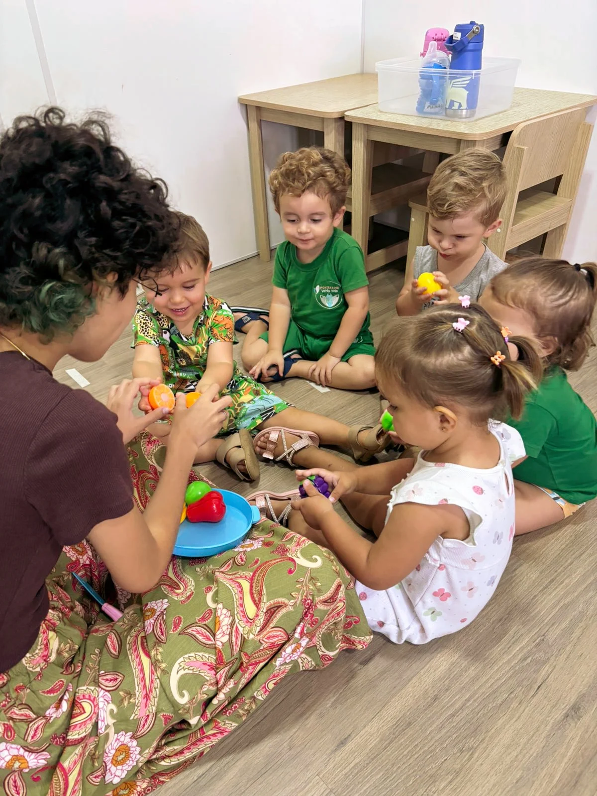 Professora e crianças reunidas em uma atividade com materiais coloridos na escola