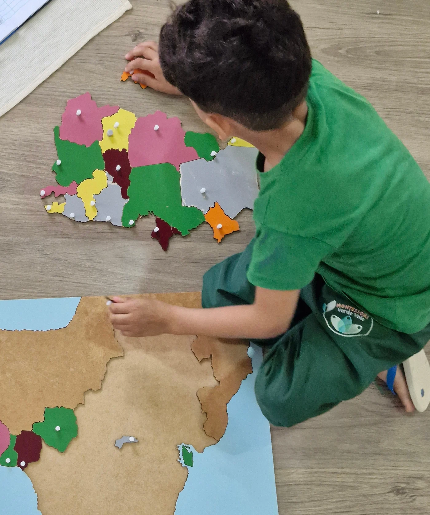 Criança montando um quebra-cabeça de mapa no ambiente preparado