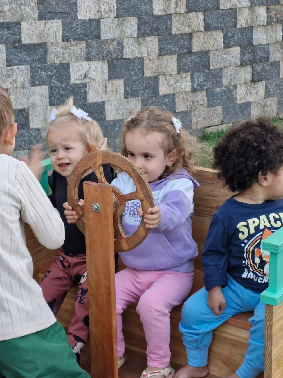 Crianças do maternal interagindo com um brinquedo de madeira